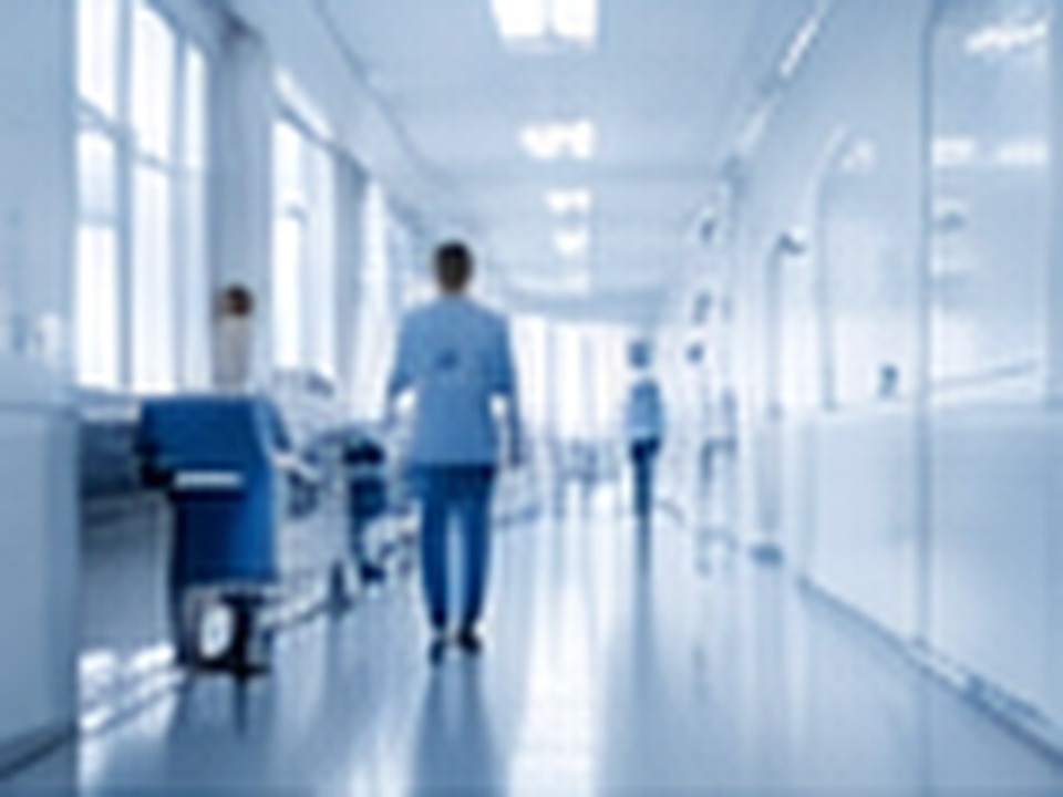 Healthcare professional walking through a modern clinical corridor.